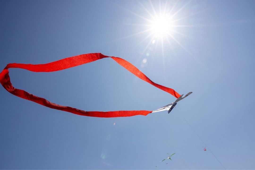 A red paper streamer floats through the air, with a bright blue sky in the background.